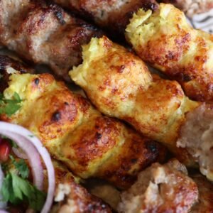 Close-up of juicy mixed kebab skewers with herbs and onions, showcasing gourmet grill marks.