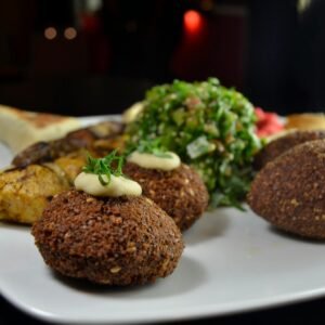 A vibrant Middle Eastern dish with falafel, kebabs, tabbouleh on a plate.