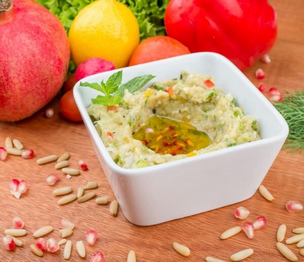 Close-up of baba ghanoush served with mint, olive oil, and fresh veggies.